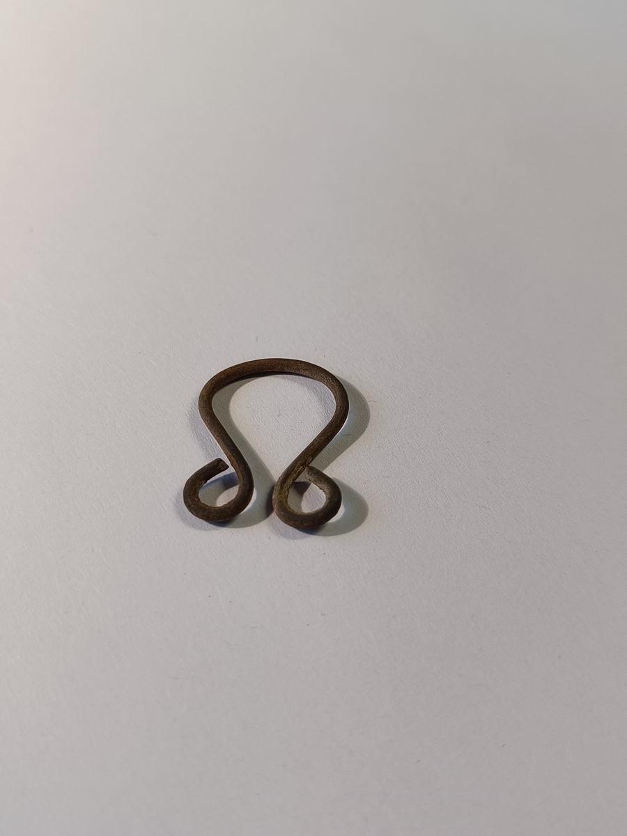 enkel og udekorert hekte laget av et stykke metalltråd. Utformingen er slik at hekta er en større bue hvor begge endene er krøllet opp i en sirkelrund avslutning. 