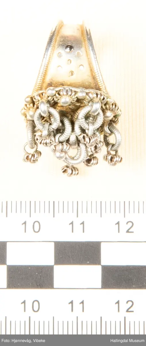 Fingerring med 10 små ringer som det er festet små ringer og "kuler" i.  2 kuler mangler. Filigransarbeid.