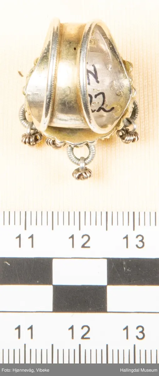 Fingerring med 10 små ringer som det er festet små ringer og "kuler" i.  2 kuler mangler. Filigransarbeid.