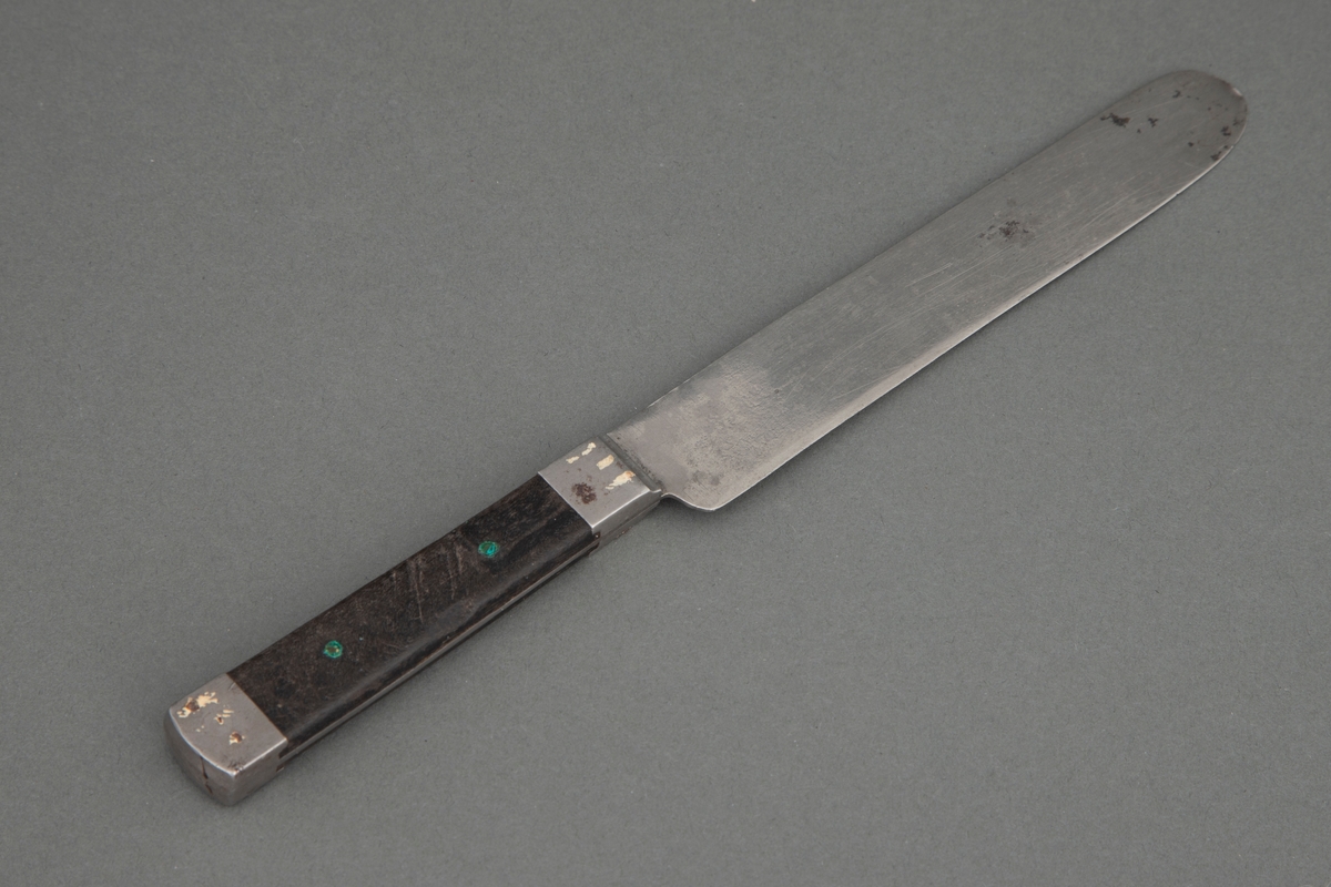 Kniv med kraftig rett blad, rundet på toppen. Bladet går gjennom hele skaftet og dekkes på over- og undersiden av mørkt tre, som er nittet fast. Ved skaftets begynnelse og ende er det et stålbeslag.