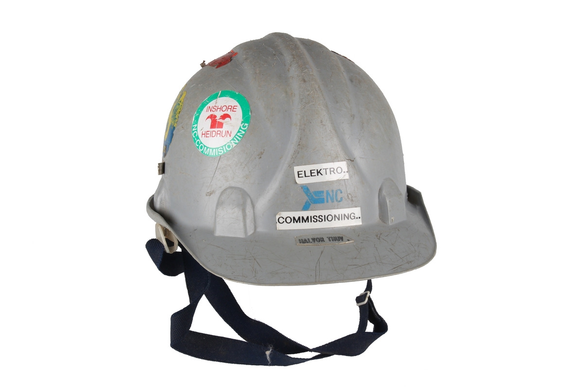 Grå vernehjelm med Norwegian Contractors sin logo og navnelapp foran.