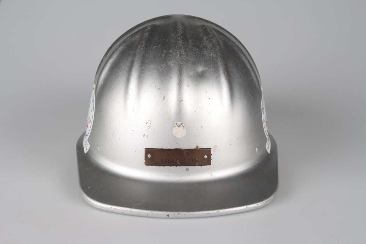 Vernehjelm med navneplate foran og med flere utvendige klistremerker.