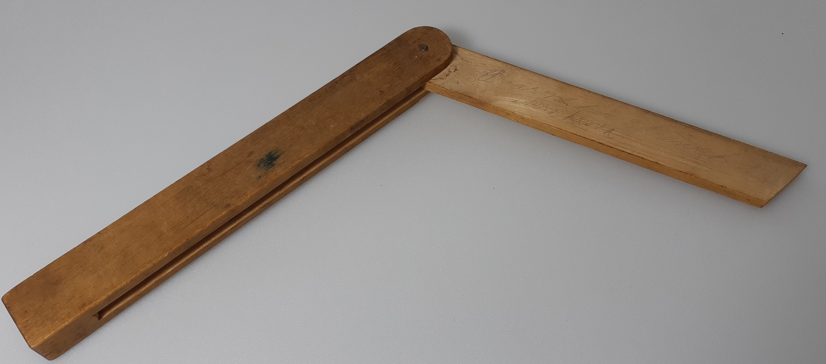 Vinkelmål i tre, sammenleggbart. Flere skriblerier med blyant langs vinkelmålet.