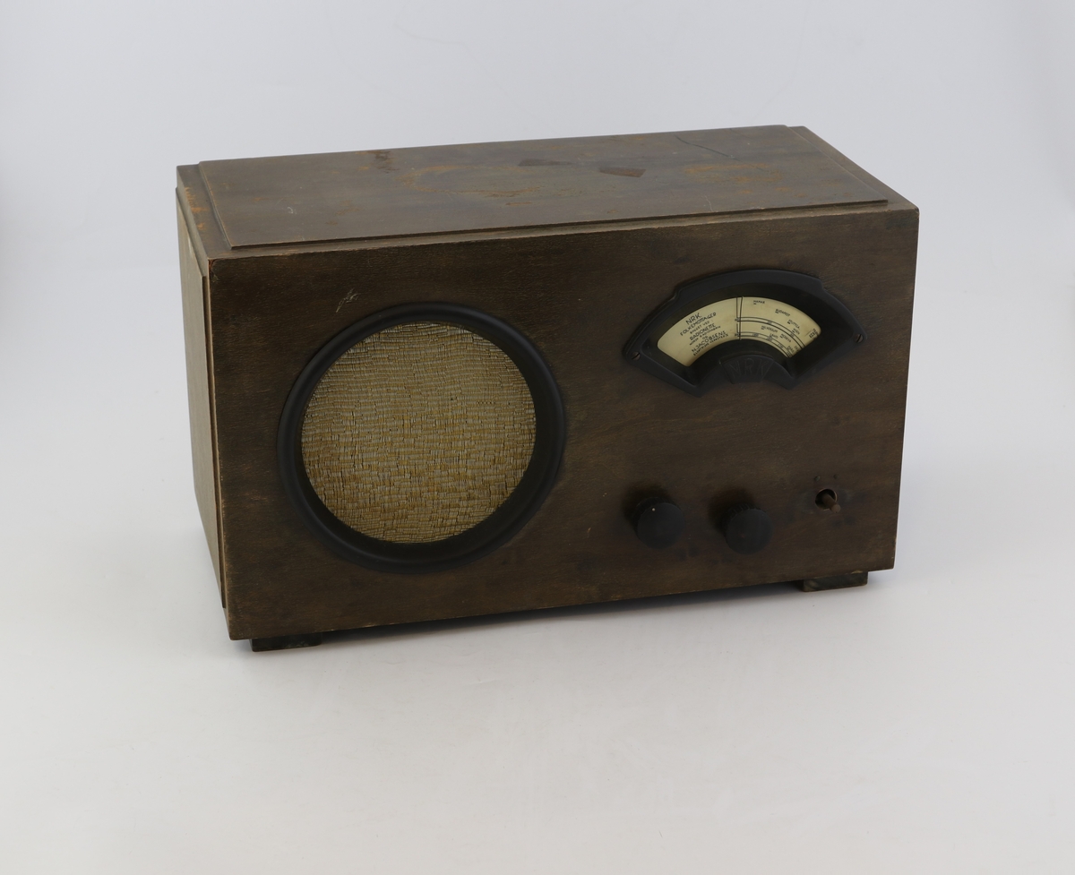 Brun rektangulær radio av tre med høyttaler, display og vridere for valg av stasjon.
