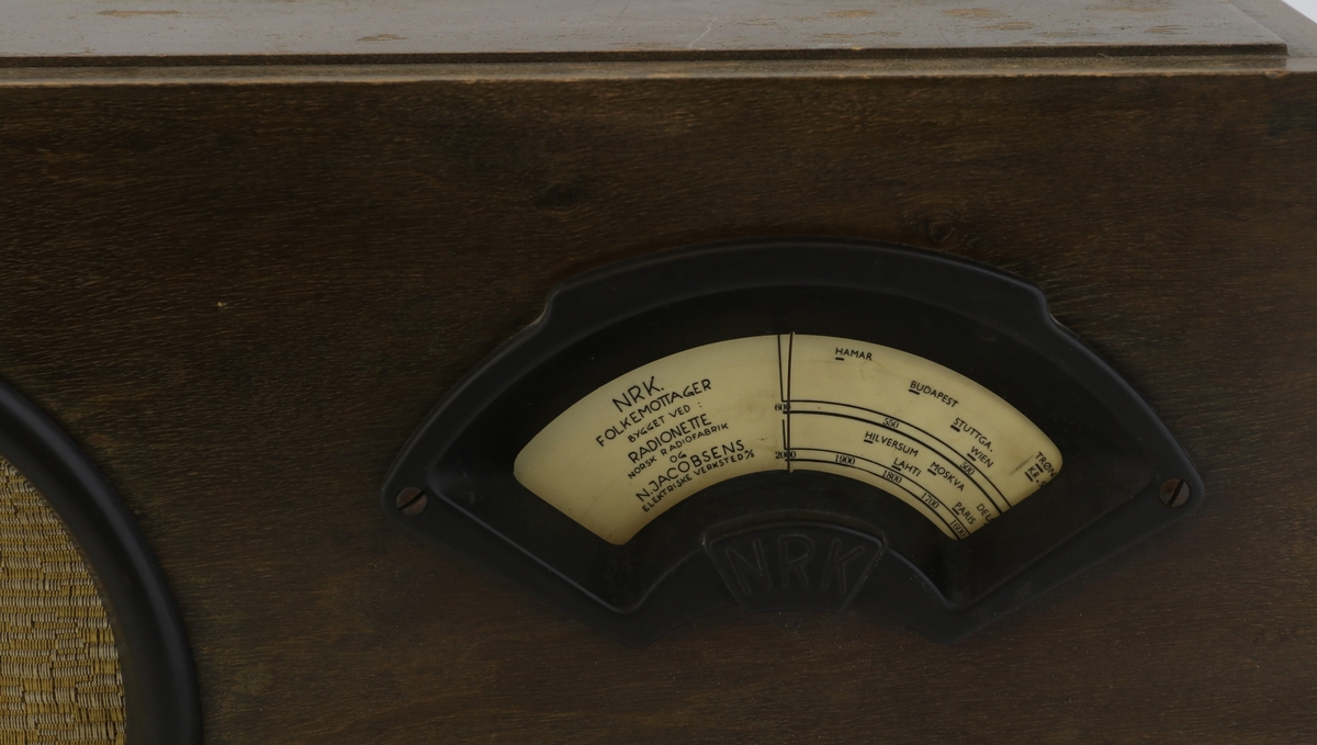 Brun rektangulær radio av tre med høyttaler, display og vridere for valg av stasjon.