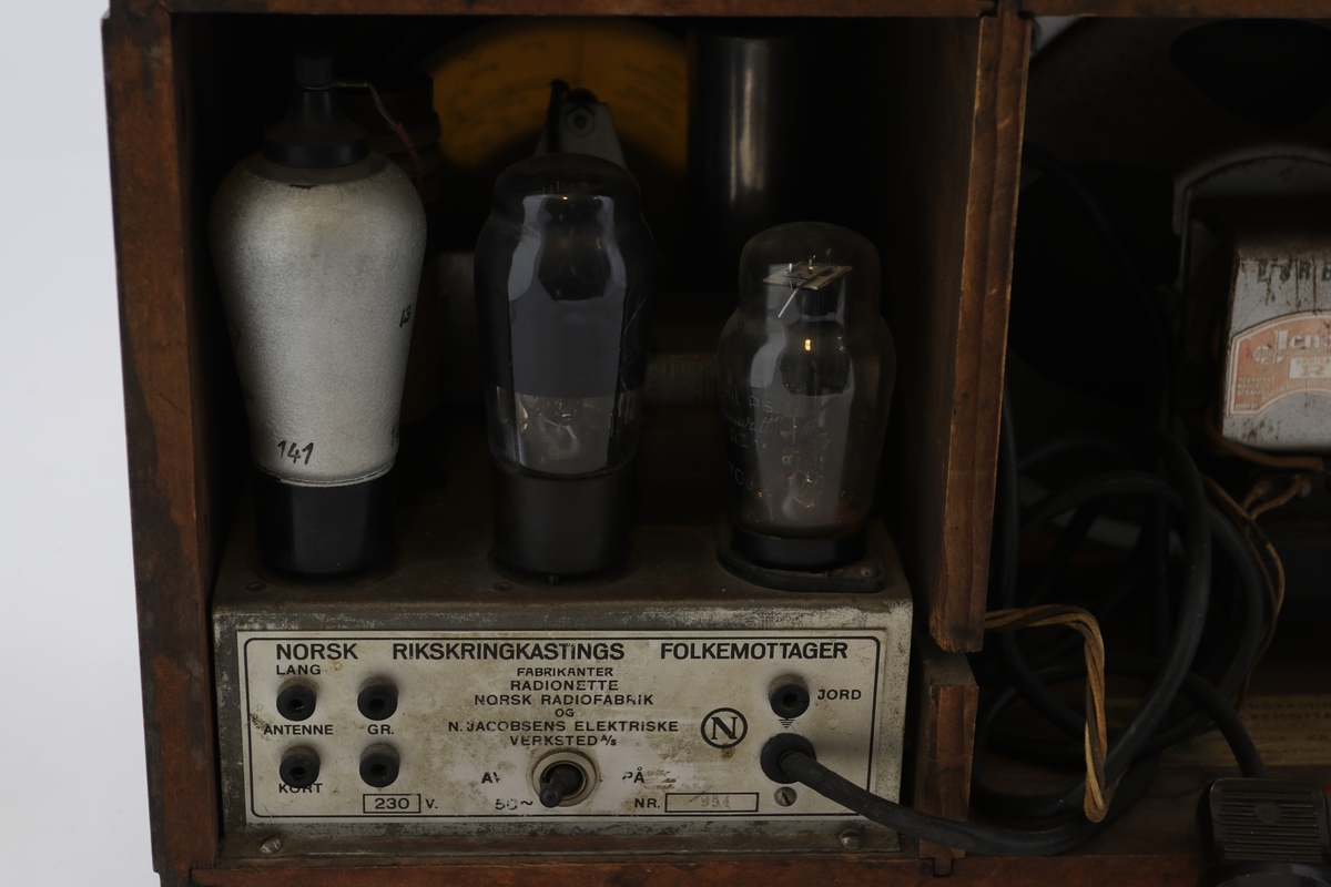 Brun rektangulær radio av tre med høyttaler, display og vridere for valg av stasjon.