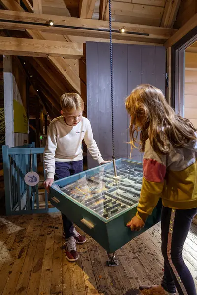 Her ser vi to barn som leker ved vippebrettet i utstillingen ressurser til låns i museet