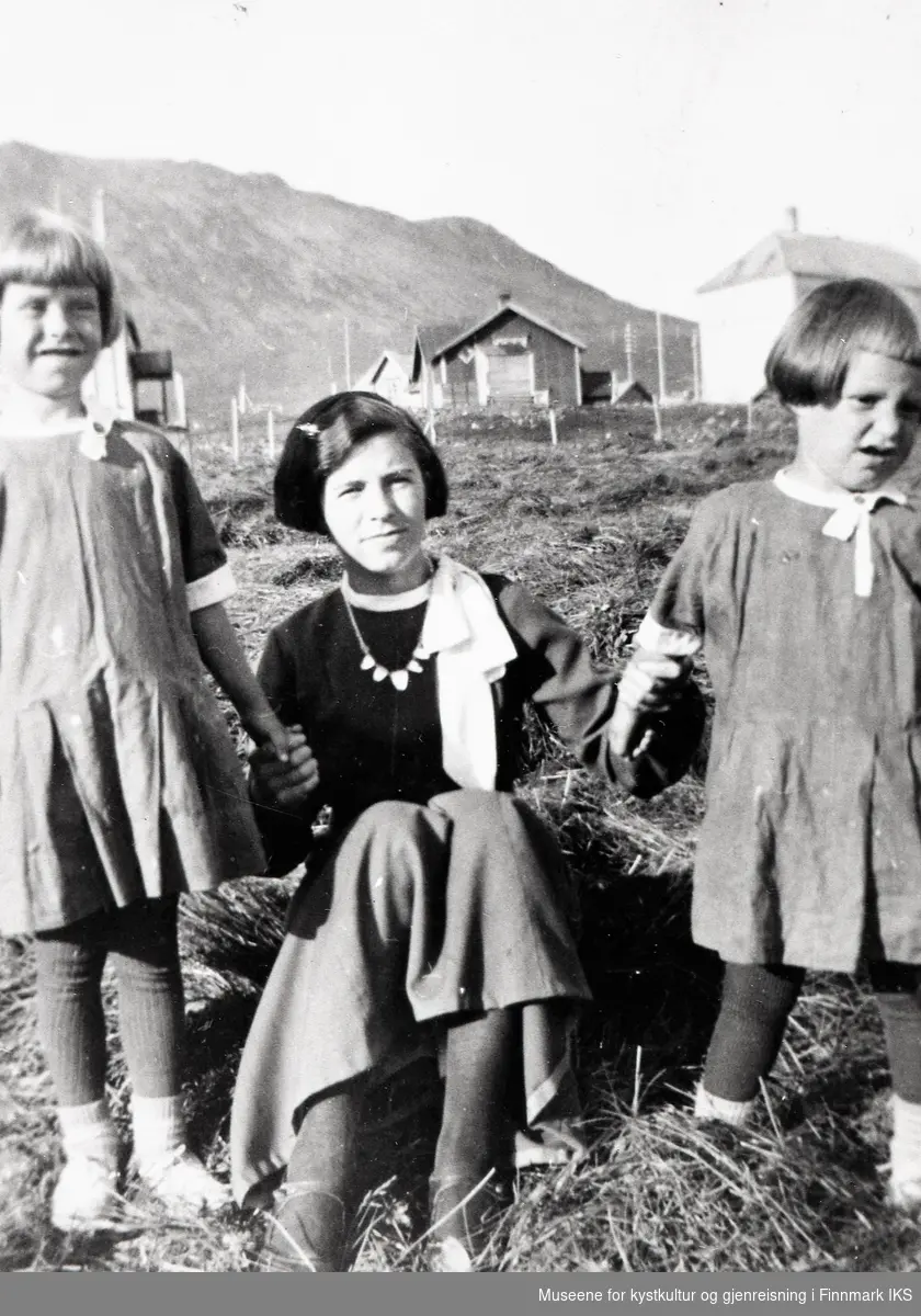 Honningsvåg. Søstrene Kitty, Edith og Haldis Andreassen på Menesjorda. Bildet er tatt på Ediths konfirmasjonsdag. Bak t.h. skolen. 1936/37.