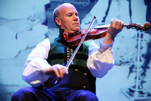 Mann i bunad som spiller hardingfele på Riksscenen