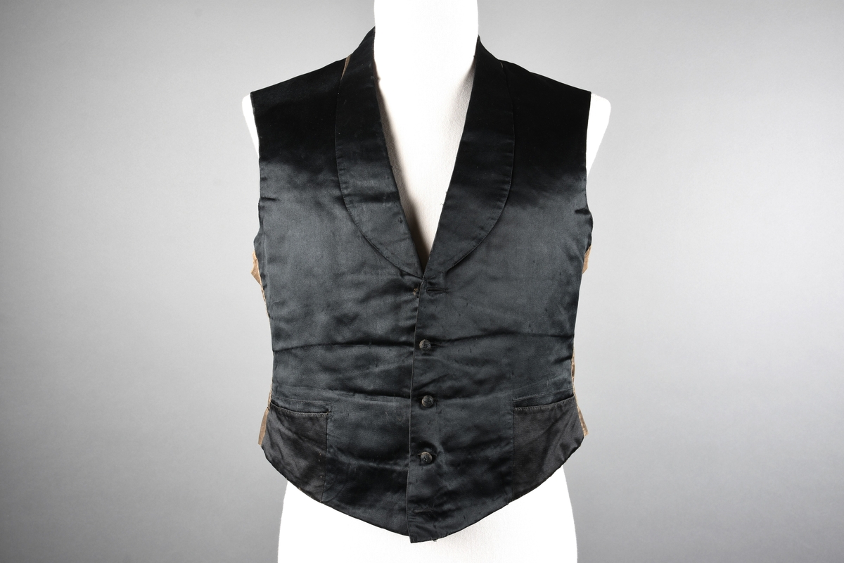 Vest av sort, blank silke. Sjalskrave. Rosa lerret innvending. Grå bak. Stoffknapper.
