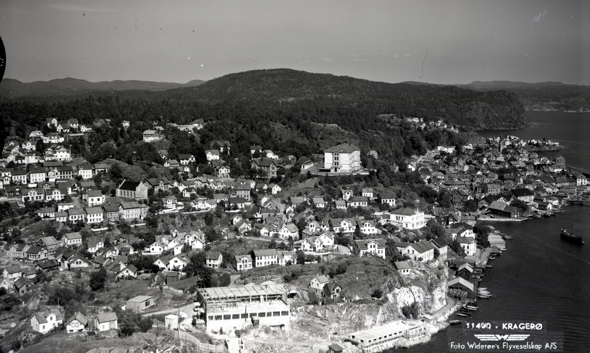 Flyfoto av Kragerø. Bygging av eldreboliger på Skrubben. Eikelandsaverksted ved vannet. Kragerø skoler.
