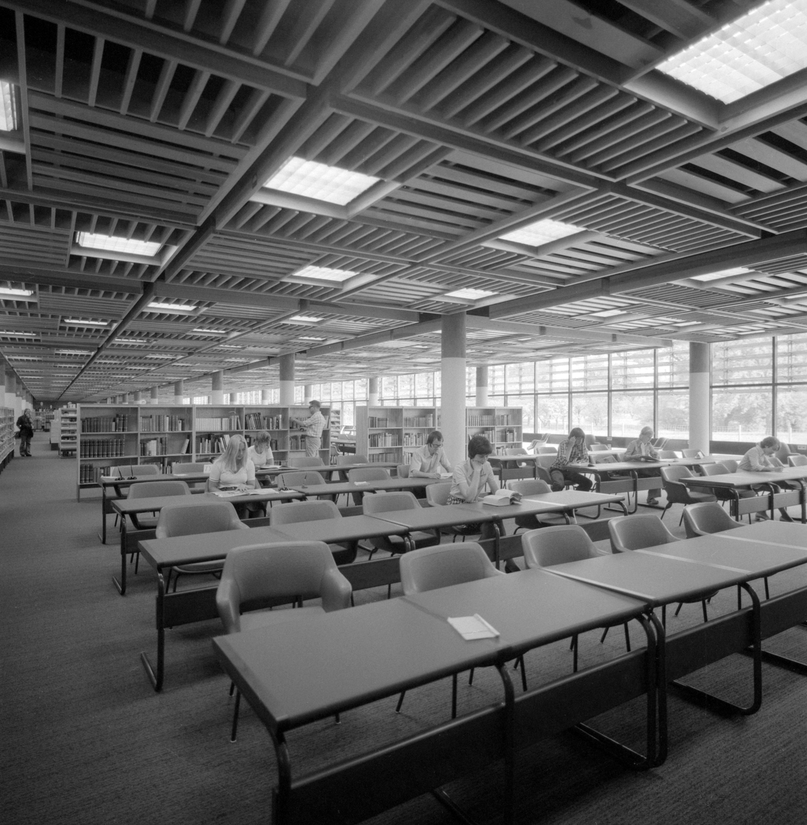 Det nya stifts- och landsbiblioteket i Linköping invigdes officiellt den 6 juni 1974 men hade då redan varit öppet för allmänheten en tid. Stort, luftigt och med all service en besökare kunde tänkas önska. Vid disken sitter bibliotekarie Gunilla Andersson och i den i studier försjunkne mannen ser vi bibliotekets mångårige medarbetare Allan Ranius.