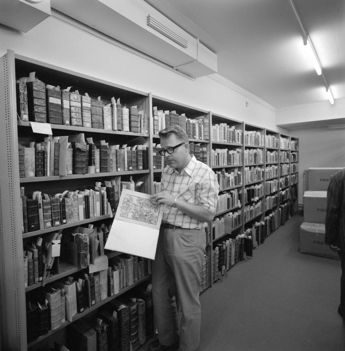 Det nya stifts- och landsbiblioteket i Linköping invigdes officiellt den 6 juni 1974 men hade då redan varit öppet för allmänheten en tid. Stort, luftigt och med all service en besökare kunde tänkas önska. Vid disken sitter bibliotekarie Gunilla Andersson och i den i studier försjunkne mannen ser vi bibliotekets mångårige medarbetare Allan Ranius.