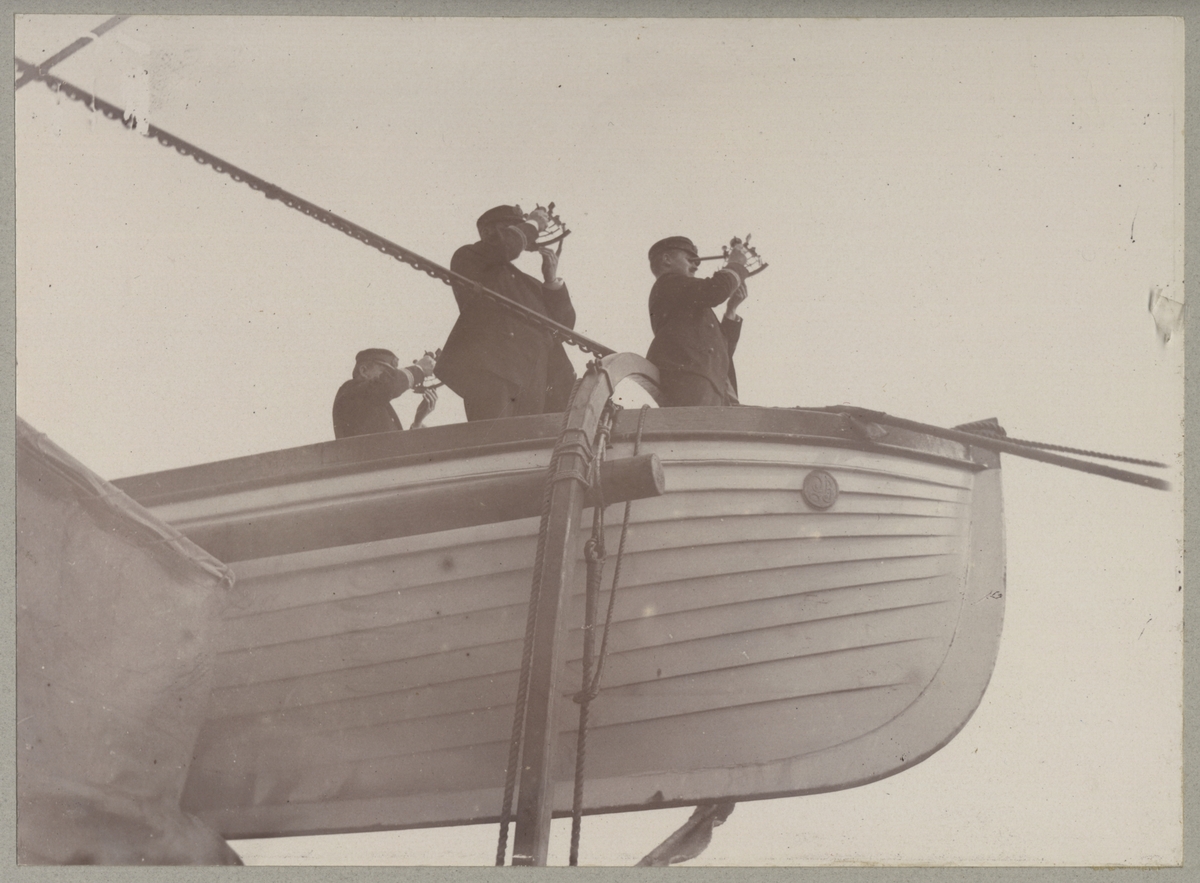 Bilden visar tre befäl som står i en livbåt och bestämmer positionen med hjälp av sextanter.