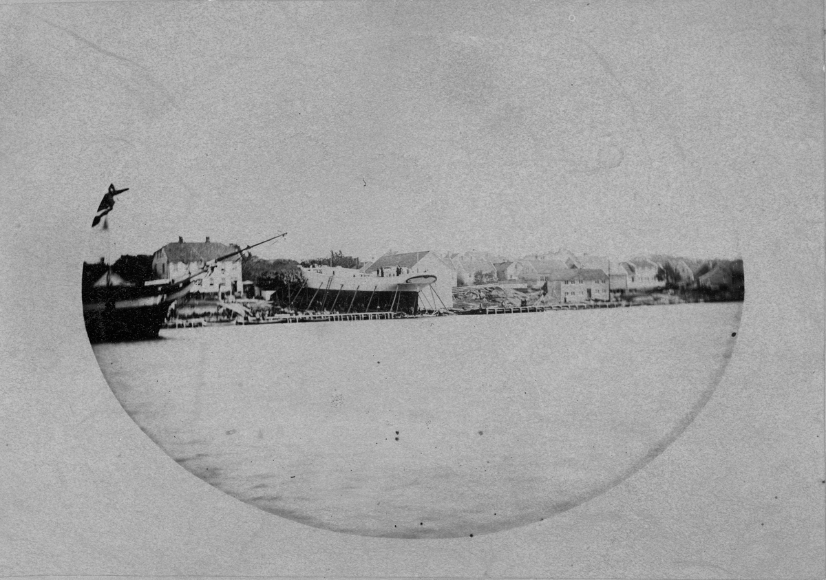 “Farvel” på Beddingen Hansens verft 1886. 
Lillesand havn med Samuel Hansens verft med stort skip på beddingen, antagelig like før stabelavløpning. 
Foto, liggende oval.