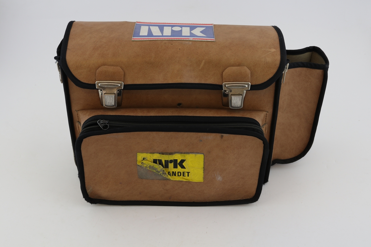 Transportabel båndopptaker med Re 50 mikrofon. Rektangulær boks med vridere, innganger og brytere på den ene langsiden. Rød toppflate med feste til bånd. Brun bæreveske merket "NRK Sørlandet" hører til.