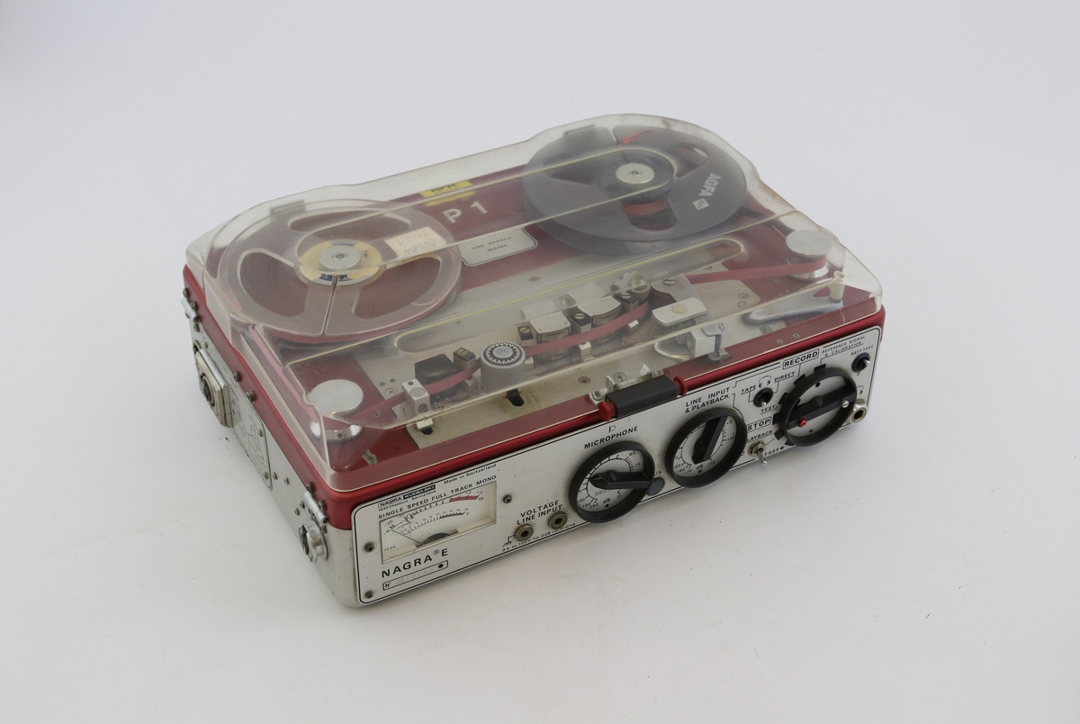 Transportabel båndopptaker med Re 50 mikrofon. Rektangulær boks med vridere, innganger og brytere på den ene langsiden. Rød toppflate med feste til bånd. Brun bæreveske merket "NRK Sørlandet" hører til.