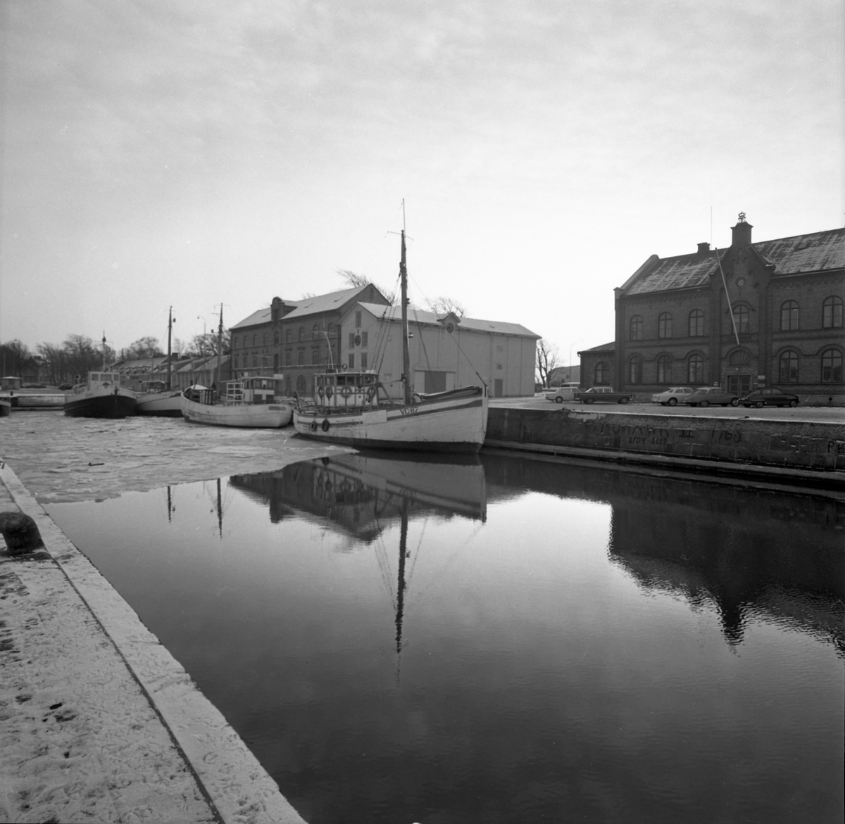 Tidningsartikel med rubriken "Fyra nyårsbåtar i Varbergs hamn" publicerad i Hallands Nyheter 1970-01-02. Till vänster ses hamnmagasinet från 1874 med Lundqvists trämagasin och till höger tullhuset. Fiskebåtar ligger vid kajen och en lastbil står mellan husen.
(Bilderna inlagda i omvänd ordning mot id-numren)