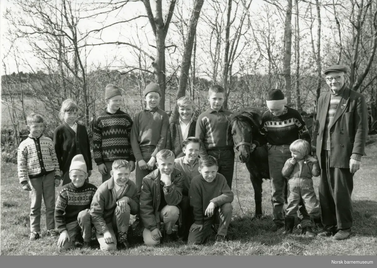 Oppstilt bilde med Lars H. Lende, tretten barn og en ponni