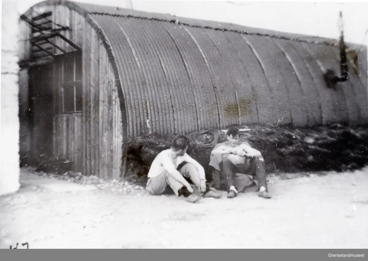 To personer sitter utenfor en Nissenbrakke og slapper av. Den første flysikring stasjonen etter krigen (1947). 