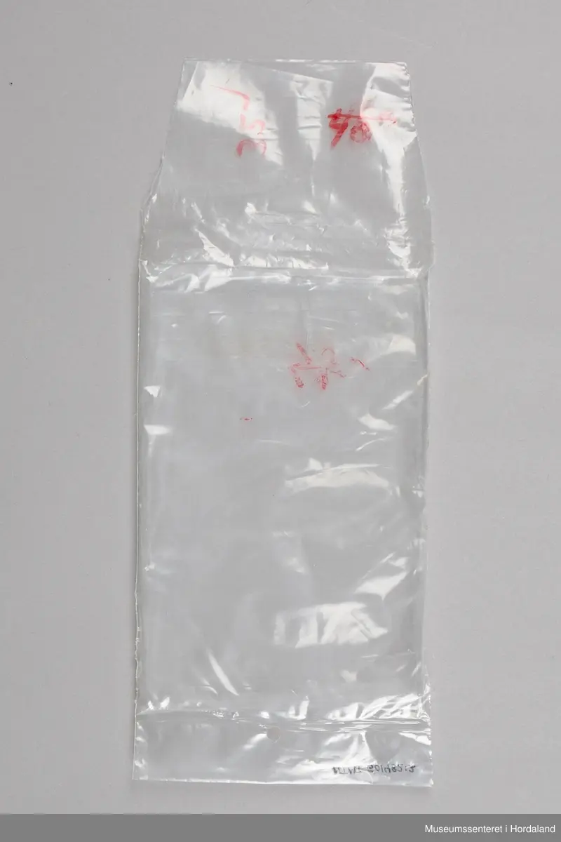 Kvit Iris brillebukse pakka i plastemballasje, med produktinformasjon. Artikkel nummer 117/2, med elastisk ribbkant. Produktinformasjonen som ligg ved gir kvalitetsgaranti, og informasjon om korleis ein kan levere tilbake plagg med feil.