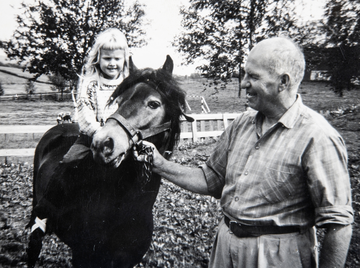 Grylling barnepensjonat og sommerleir, Løten. Jon Karterud godsnakker med hesten mens den har ei jente på ryggen. Garden Grylling vestre, Nordbygda, Løten. 1950-tallet. Hestene var alltid populære for barna på Grylling barnepensjonat og sommerleir.