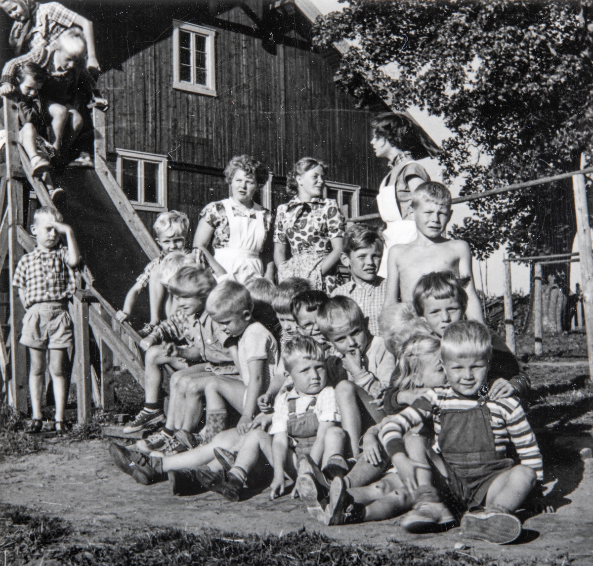 Grylling barnepensjonat og sommerleir, Løten. Stas å bli fotografert. Kjell Karterud bak til høyre (med bar overkropp). Mange aktiviteter å finne på ute på gardstunet, lekeapparater, barn. Garden Grylling vestre, Nordbygda, Løten. 
1950-tallet. Grylling barnepensjonat og sommerleir.