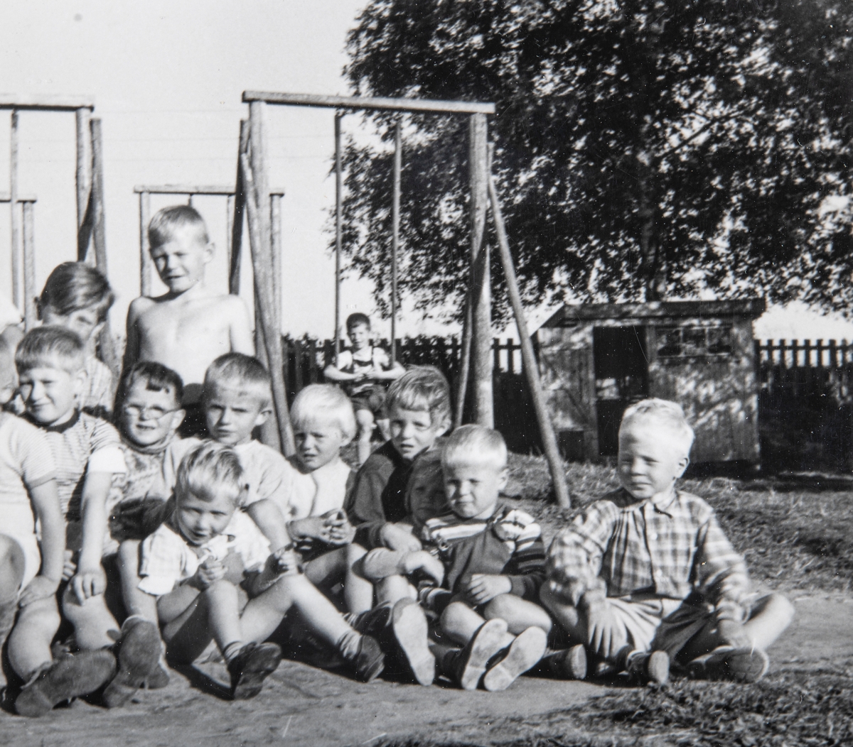 Grylling barnepensjonat og sommerleir, Løten. Stas å bli fotografert. Kjell Karterud bakerst med bar overkropp. Mange aktiviteter å finne på ute på gardstunet, lekeapparater, barn. Garden Grylling vestre, Nordbygda, Løten. 
1950-tallet. Grylling barnepensjonat og sommerleir.