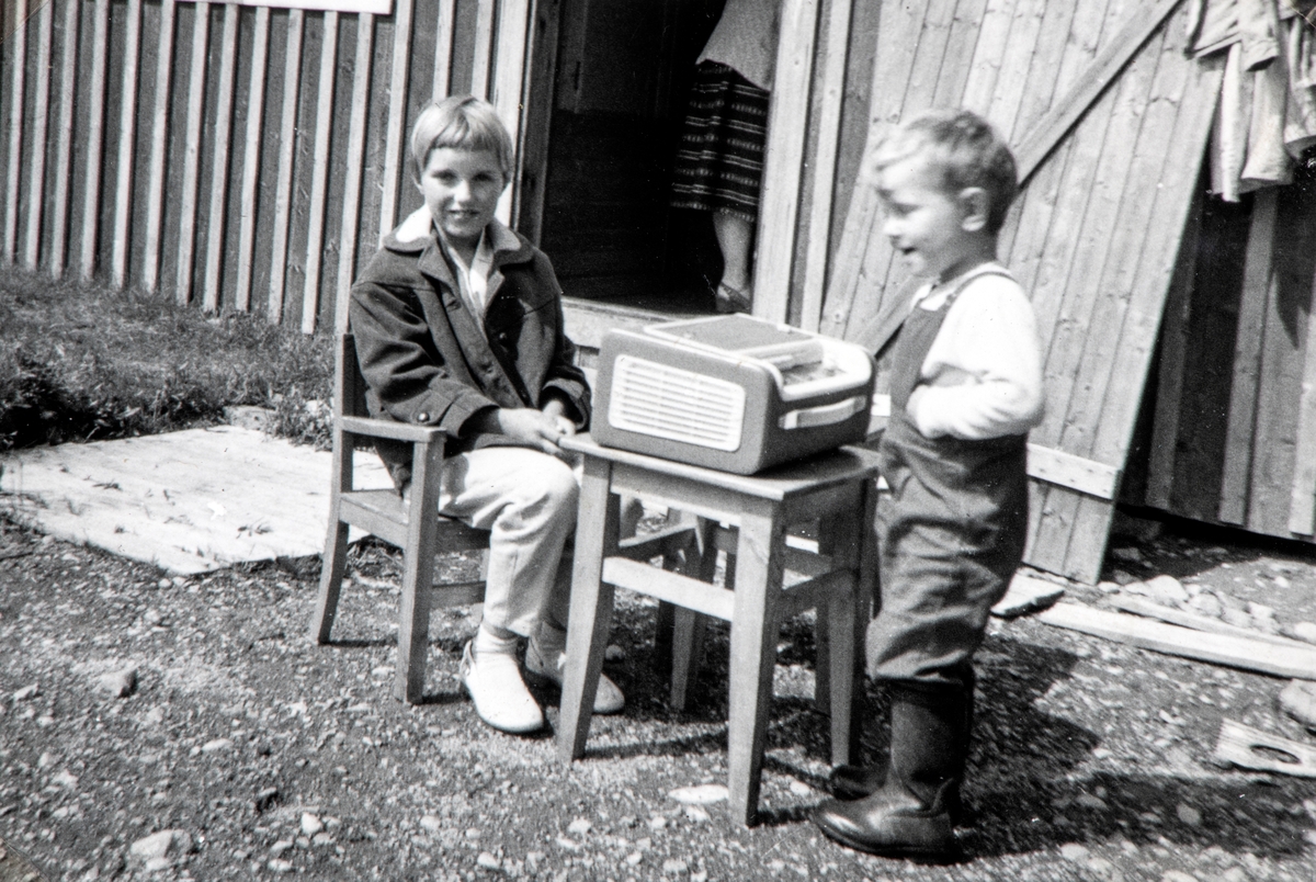 2 barn hører på radio. Fra venstre: Wenche Furulund  og Trond Furulund. Bilde fra Henrik Furulund og Nils Nylunds hytte på Grunnåsen i ca. 1960 .