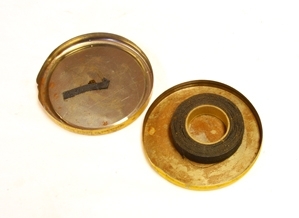 Eske. Metall. Sirkulær overdel trees over underdel. Skrift. Illustrasjon av mann med isolerband. Rull med brunt isolerband.