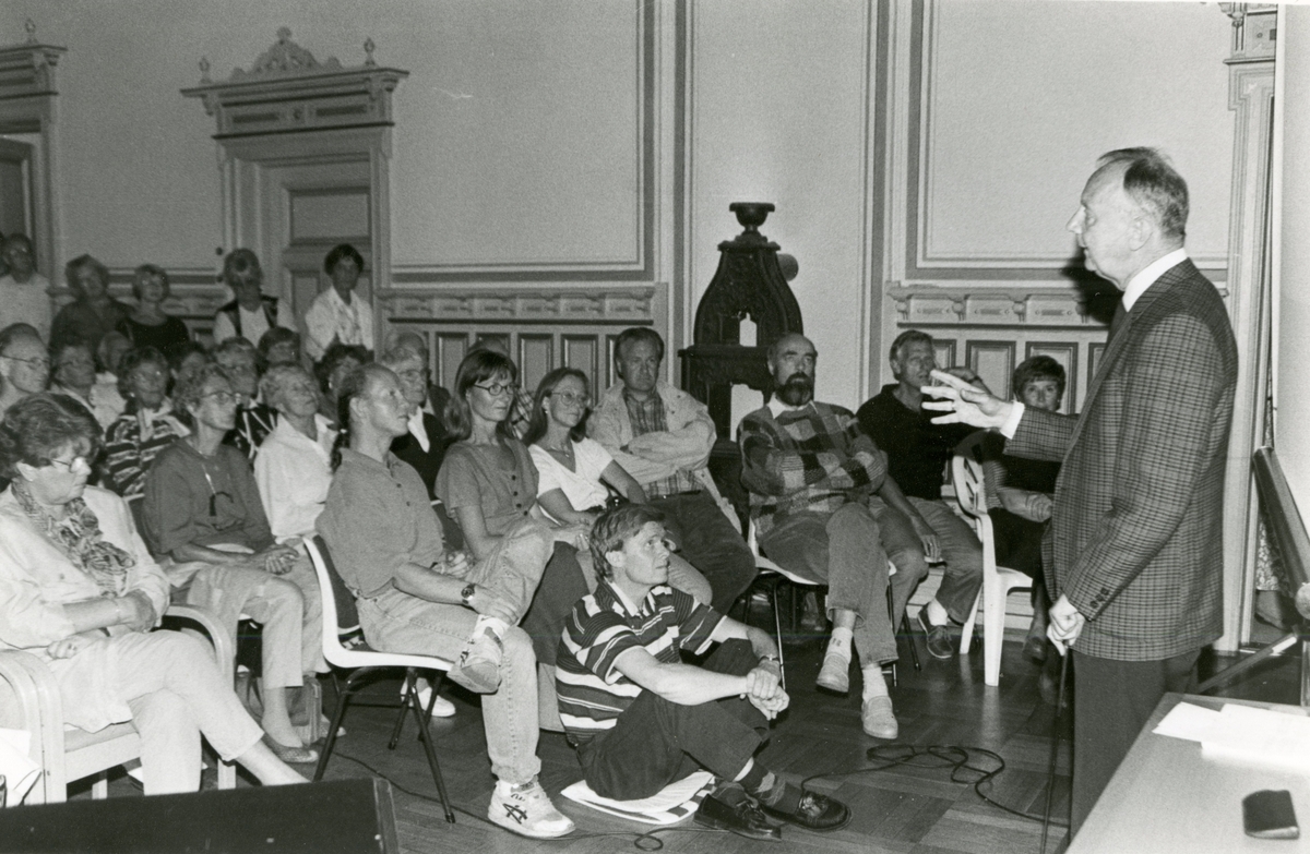 Carsten Hopstock kåserer i legatsalen. Første rad: Aksel Hopstock, Ingunn Næs, Anne Hopstock, ?, Storheier.