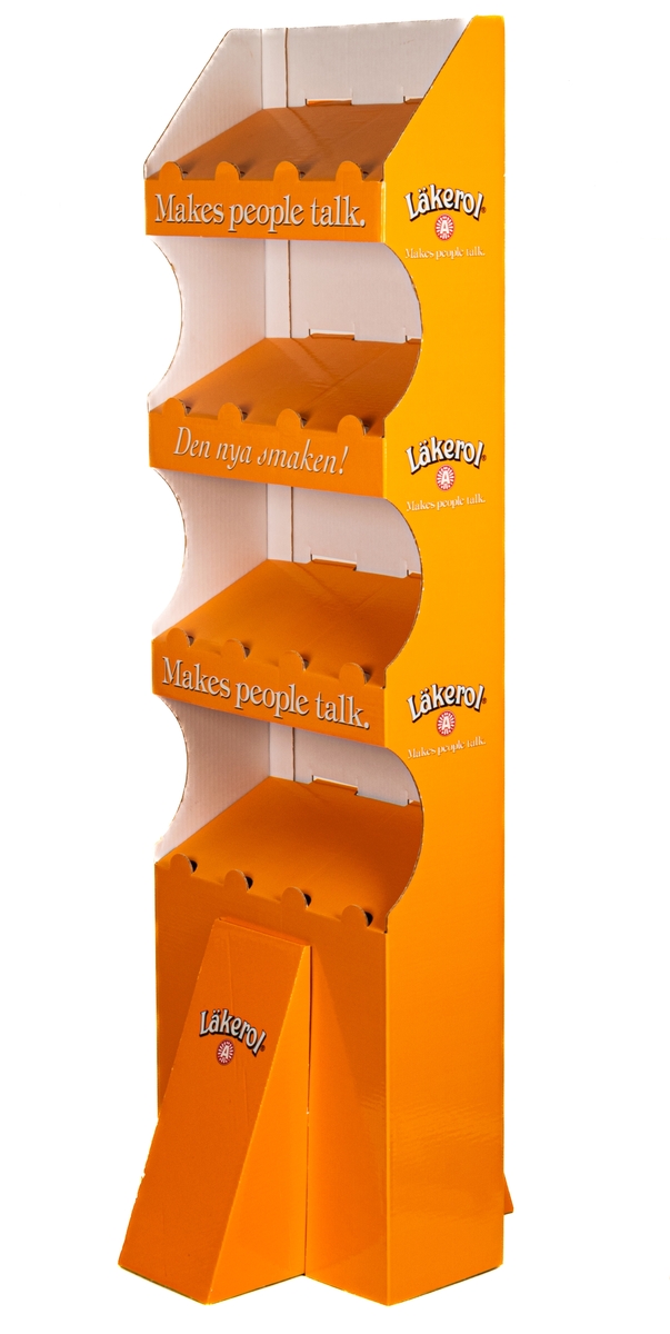 Reklamställ i papp, orange och vitt. Fyra fack för reklamartiklar. Tryckt text: Läkerol Make people talk.