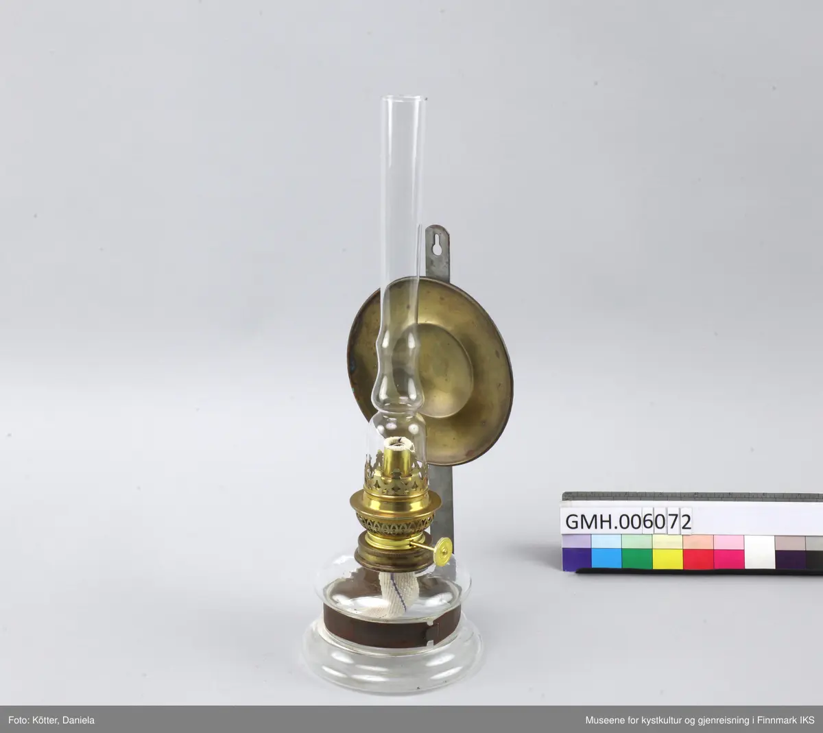 Lampen består av et glassbeholder som omfavnes av en metallspenne. Spenna er festet til en flat, vertikal metallstang som har et hull øverst for å henges på veggen. Ved metallstanga er det også festet en rund speil av messing som skal reflektere kampens lys. Øverst ved glassbeholderen skrues det fast en anordning med en mekanisme som tillater å justere veiens lengde samt at man setter på et glassrør for å beskytte flammen. 