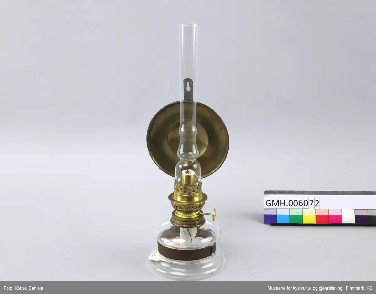 Lampen består av et glassbeholder som omfavnes av en metallspenne. Spenna er festet til en flat, vertikal metallstang som har et hull øverst for å henges på veggen. Ved metallstanga er det også festet en rund speil av messing som skal reflektere kampens lys. Øverst ved glassbeholderen skrues det fast en anordning med en mekanisme som tillater å justere veiens lengde samt at man setter på et glassrør for å beskytte flammen. 