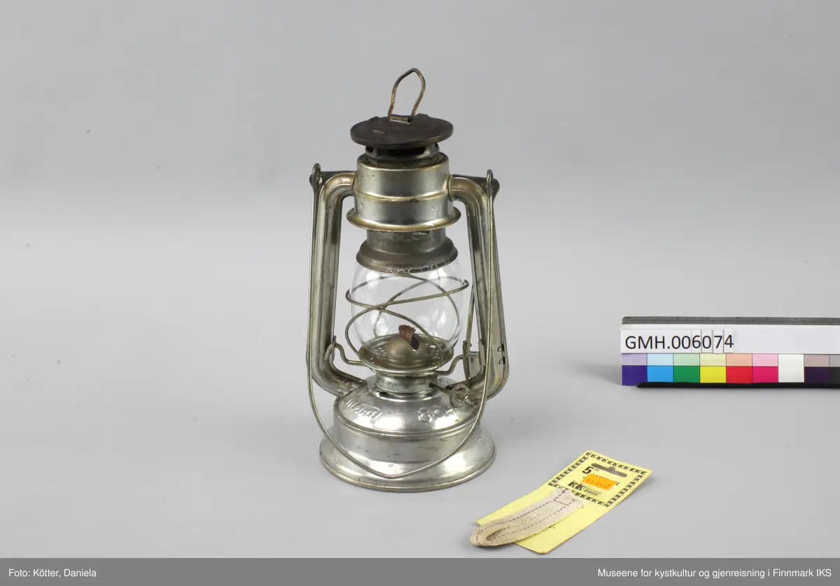 Lampen er laget av aluminium. Foten er brennstoffbeholderen. På den skrues det fast justermekanismen for veken. Lengden av veken justeres med en liten spak på siden. Glasset sitter i to bøyler og kan løftes ved å klaffe ned en liten spak. På hver side har lampa staver som går opp mot hetta med luftehull. Øverst er det en metalløkke til oppheng og lampa kan bæres ved en metallbøyle. Med lampen følger det en ny veke