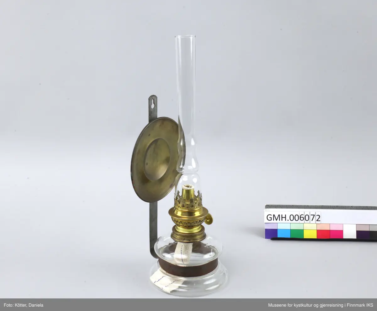 Lampen består av et glassbeholder som omfavnes av en metallspenne. Spenna er festet til en flat, vertikal metallstang som har et hull øverst for å henges på veggen. Ved metallstanga er det også festet en rund speil av messing som skal reflektere kampens lys. Øverst ved glassbeholderen skrues det fast en anordning med en mekanisme som tillater å justere veiens lengde samt at man setter på et glassrør for å beskytte flammen. 