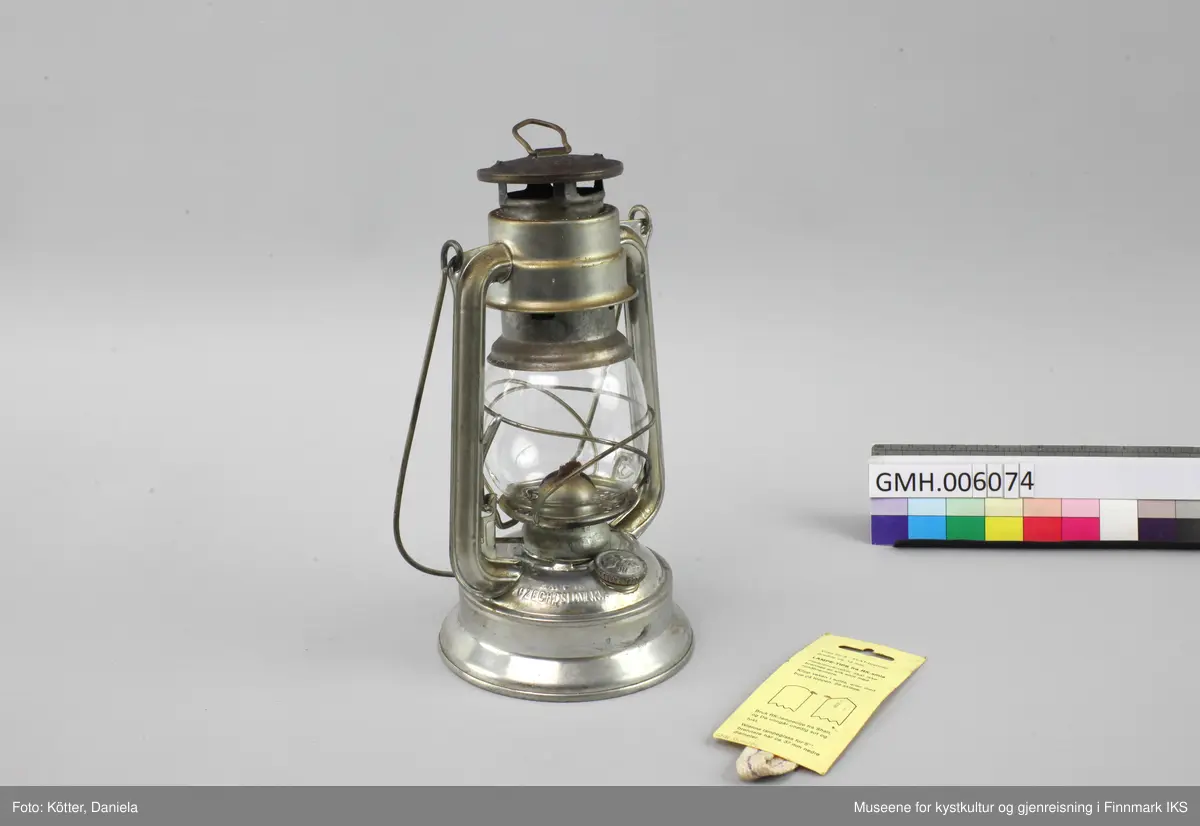 Lampen er laget av aluminium. Foten er brennstoffbeholderen. På den skrues det fast justermekanismen for veken. Lengden av veken justeres med en liten spak på siden. Glasset sitter i to bøyler og kan løftes ved å klaffe ned en liten spak. På hver side har lampa staver som går opp mot hetta med luftehull. Øverst er det en metalløkke til oppheng og lampa kan bæres ved en metallbøyle. Med lampen følger det en ny veke