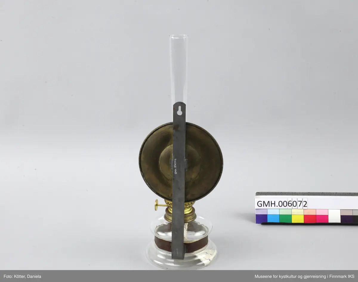 Lampen består av et glassbeholder som omfavnes av en metallspenne. Spenna er festet til en flat, vertikal metallstang som har et hull øverst for å henges på veggen. Ved metallstanga er det også festet en rund speil av messing som skal reflektere kampens lys. Øverst ved glassbeholderen skrues det fast en anordning med en mekanisme som tillater å justere veiens lengde samt at man setter på et glassrør for å beskytte flammen. 