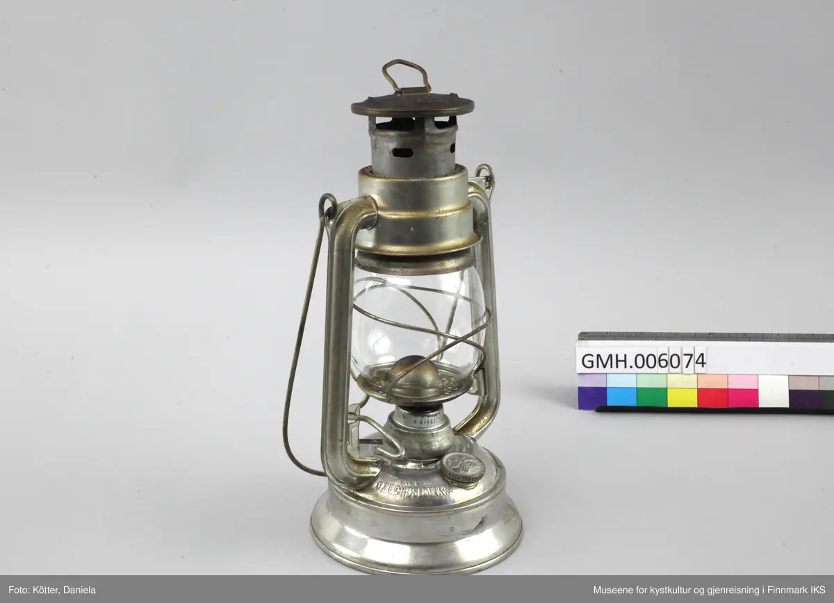 Lampen er laget av aluminium. Foten er brennstoffbeholderen. På den skrues det fast justermekanismen for veken. Lengden av veken justeres med en liten spak på siden. Glasset sitter i to bøyler og kan løftes ved å klaffe ned en liten spak. På hver side har lampa staver som går opp mot hetta med luftehull. Øverst er det en metalløkke til oppheng og lampa kan bæres ved en metallbøyle. Med lampen følger det en ny veke