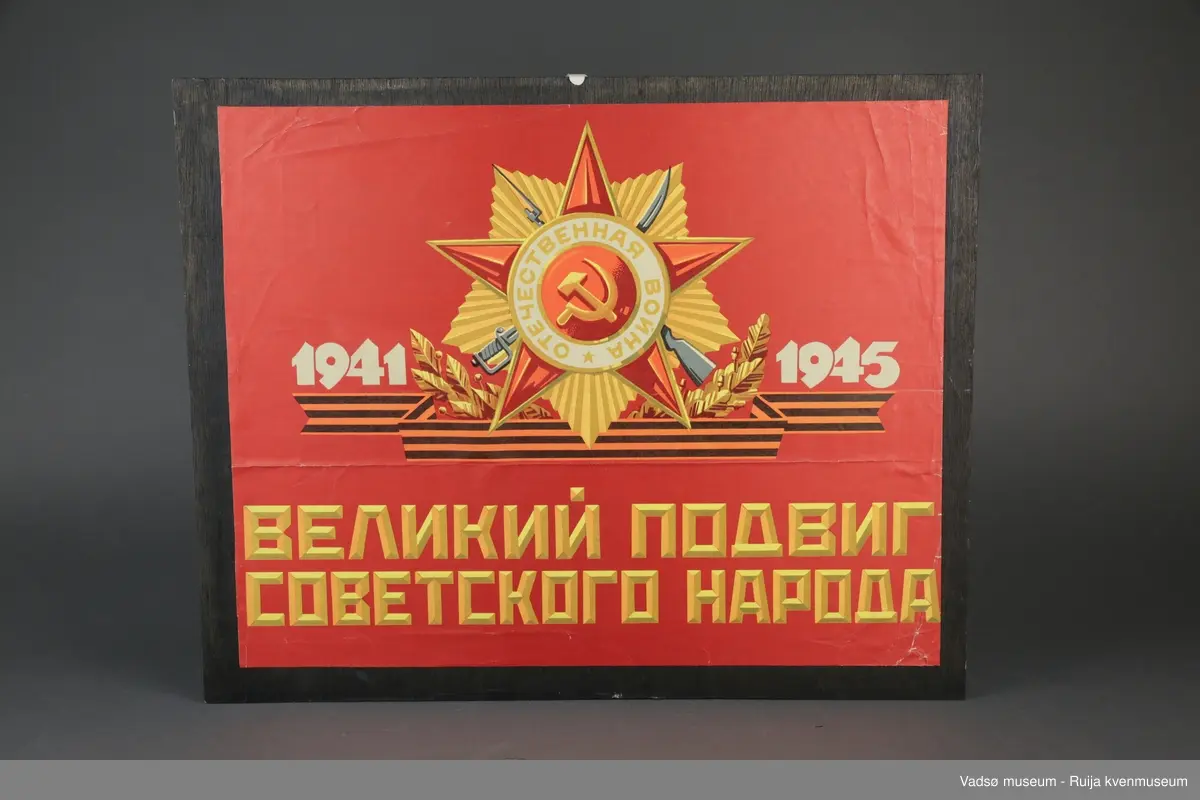 Sovjetisk plakat limt på hjemmeprodusert bakplate av brunmalt veggpanel. Russisk påskrift oversatt til norsk: "Stor heltedåd av det sovjetiske folk."