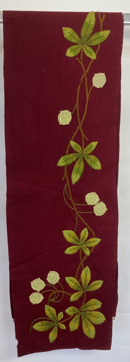 Ull, filt, ullgarn, silkegarn.
Løper ull, filt, dyprød.
Broderte bladranker, tre grønne
farger, en brun. Blomster hvit filt,
brodert med hvit silke, grønne ull
stilker.
Fire stykk messingringer på en kortside.
