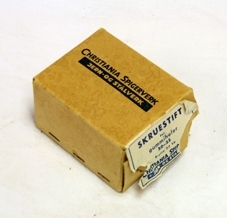 Eske m/skruestifter. Lys brun papp. Stiftet sammen. Åpnes i begge ender med klaffer. Etikett i papir i den ene enden. Skrift på begge langsidene. Rektangulær. Inneholder skruestifter.