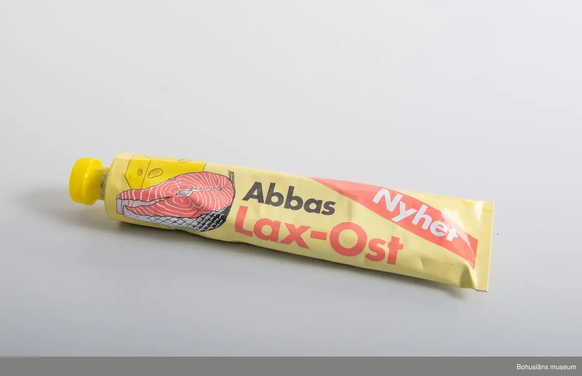 471 Tillverkningstid 1975-1985
410 Mått/Vikt !L 21, B 5,5CM
106 OCM *255,348
594 Landskap BOHUSLÄN
503 Kön MAN
394 Landskap BOHUSLÄN
601 Tub med tryckt dekor i gult,rosa,vitt och svart. Gjutet,gult skruvlock
603 Text;"ABBAS Lax-Ost. Nyhet."På baksidan innehållsförteckning
604 samt streckkod för prismärkning. Identisk med  UM 26816
605 Om givaren se UM 26667