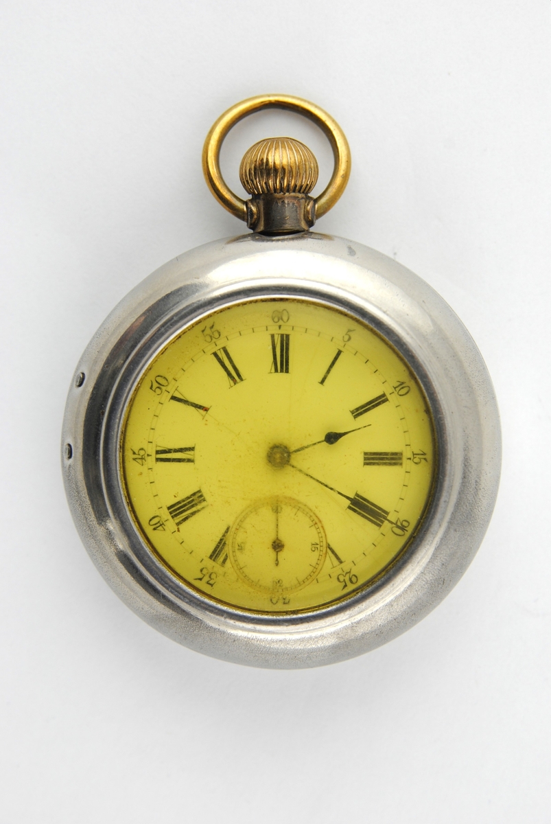 Herrmodell med förnicklat fodral. Boetten i silver och guld. Rikt graverat på baksidan. Stämplad DMF o CO på insidan locket och innanför Cylindre o Rubis. Urtavlan har romerska siffror, minutsiffror vid varje 5 minuter i arabiska siffror. Separat sekundvisare nertill. Kron uppdragning.