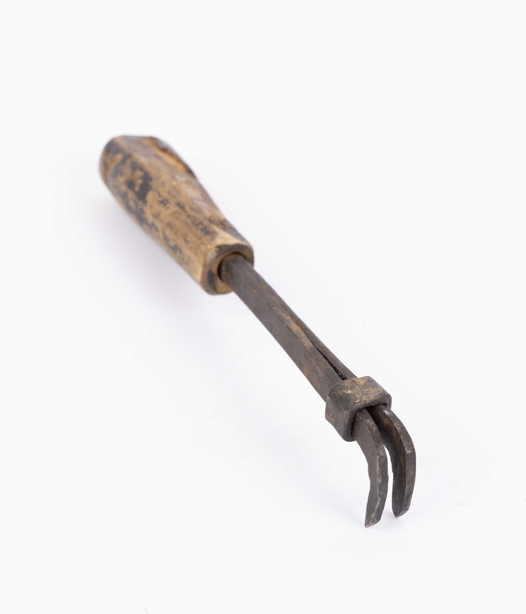 Meddrag i jern og med treskaft dekorert med utskjært X på begge sider av skaftet. To jern satt sammen og justeres med en rektangulær jernring.