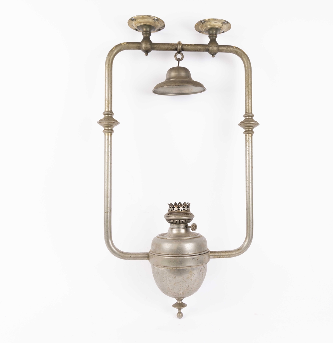 Parafinlampe fra skip tilhørende Det Bergenske Dampskibsselskab. Lampe i oppheng for tak i skipssalong. Sylinderformet lampeglass mangler. Utført i forkrommet metall, større bulk på parafinbeholder.