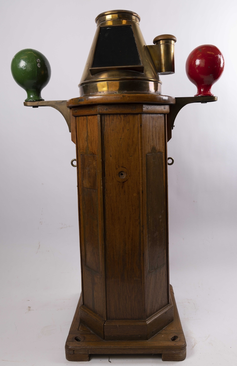 Natthus i tre og messing med kompass produsert av C. Plath. Med to kvadrantkuler, samt klargjort for tilkobling til elektrisk lys på høyre side. Med flinders stang montert bakpå sokkel. Har vært ombord i skip tilhørende J.L. Mowinckels Rederi. Klinometer i front mangler.