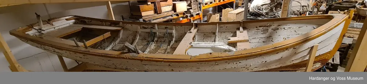 Lettbåt fra selfanger med to tofter i baugen med en lav vegg imellom, to par tollepinner på styrbord side, bredt sete i akter, samt ror med rorkult og en åragaffel festet til akterspeilet. Båten er hovedsakelig hvitmalt med okergule kanter og seter, blått ror, og den er rødmalt under bunnen. Båten er klinkbygget.