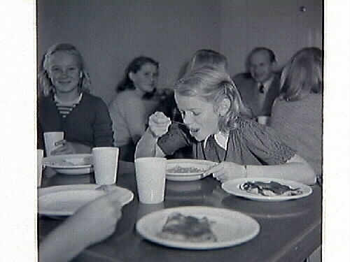 Barnbespisningen till skolan i Spannarp 1949 med byggnaden samt ätande elever och personal.