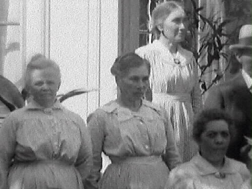 Gruppbild av människor utanför en villa. Möbelhandlare C J Carlsson beställde bilden och är troligen själv med.